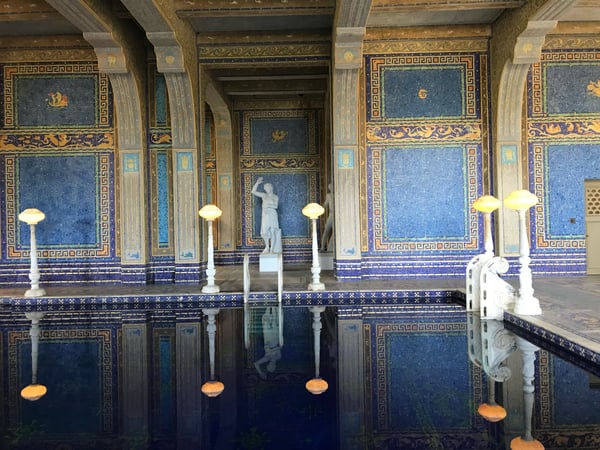 Roman-style indoor pool with blue mosaic tiles, Greek key patterns, and classical sculptures at Hearst Castle. — Hearst Castle, Big Sur & the Highway 1 Coast
