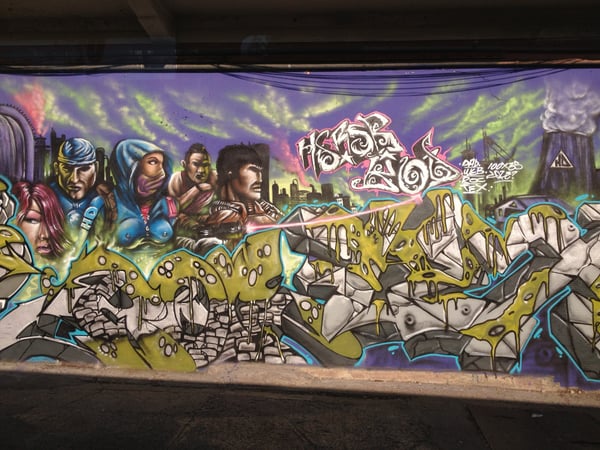 Elaborate graffiti mural with sci-fi characters and stylized lettering on an underpass wall in San Juan, Puerto Rico.