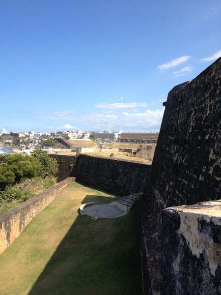 View from within Fort San Felipe del Morro's moat and fortification walls overlooking San Juan's coastal cityscape. — Faro del Castillo San Felipe del Morro, San Juan