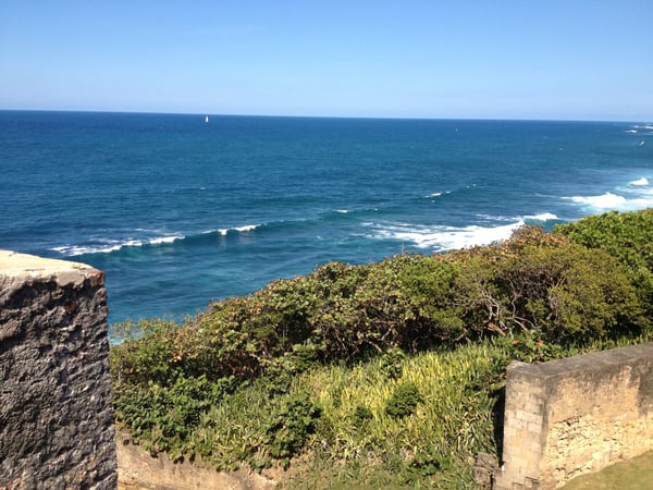 Atlantic Ocean and coastal cliffs viewed from Castillo San Felipe del Morro in San Juan, Puerto Rico, with sailboat on… — Faro del Castillo San Felipe del Morro, San Juan
