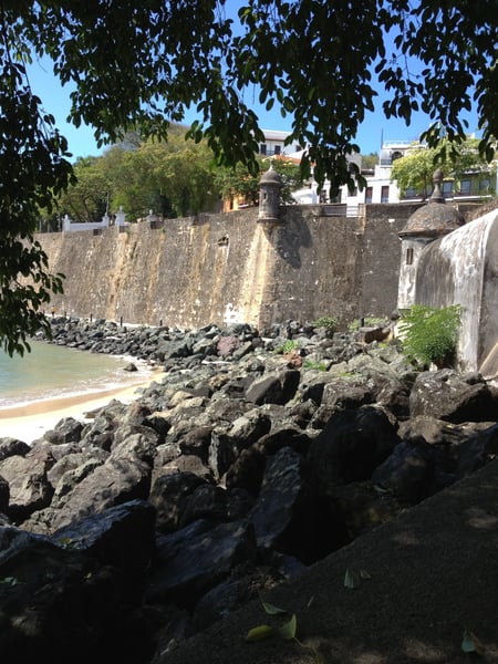 Colonial-era fortification wall with sentry tower overlooking a rocky coastline and beach in Old San Juan, Puerto Rico. — Plazuela de Isabel I de Castilla, San Juan