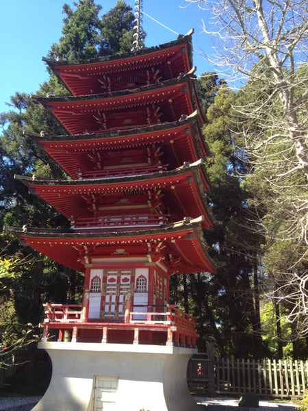 A five-tiered red Japanese pagoda with ornate eaves and white base structure surrounded by trees in Golden Gate Park. — Golden Gate Park, San Francisco