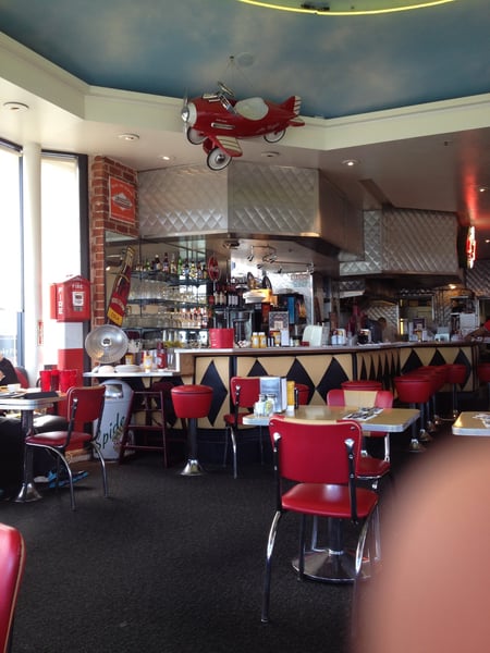 Retro 1950s diner interior with red vinyl seating, aircraft ceiling decoration, and geometric bar pattern at… — San Francisco