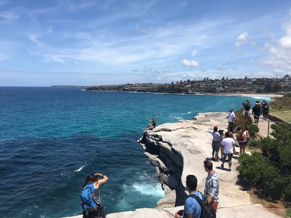 Mackenzie's Point Lookout overlooks turquoise waters and a coastal headland, with visitors gathered on the sandstone… — Tamarama, Sydney