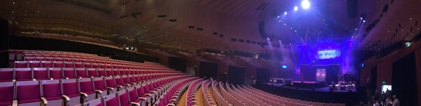 Interior of a large concert hall with red seats and illuminated stage setup during an event. — Sydney Opera House, Sydney