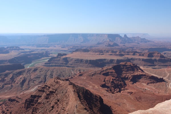 Aerial view of layered red rock formations, mesas, and a winding river through an arid desert landscape near Moab, Utah. — Dead Horse Point State Park, Moab, Arches & Canyonlands