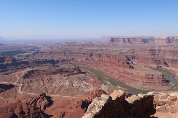 Dead Horse Point overlook showing the Colorado River winding through red rock canyons and mesas under clear blue sky. — Moab, Arches & Canyonlands