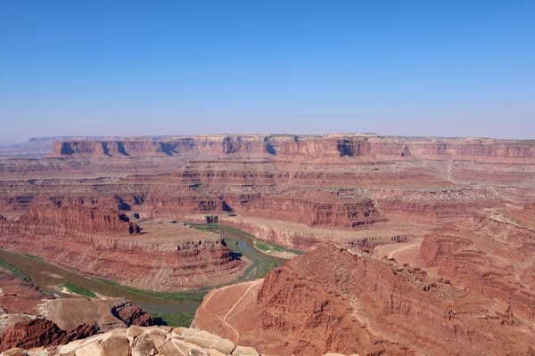Dead Horse Point overlook showing a meandering river through layered red rock canyons and distant plateaus under clear… — Moab, Arches & Canyonlands