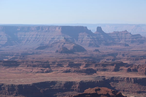 Vast desert landscape with layered rock formations and buttes viewed from an elevated overlook in Moab, Utah. — Dead Horse Point State Park, Moab, Arches & Canyonlands