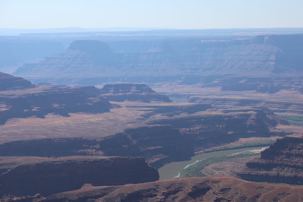 Aerial view of layered desert plateaus and a winding river through arid canyonlands near Moab, Utah. — Dead Horse Point State Park, Moab, Arches & Canyonlands