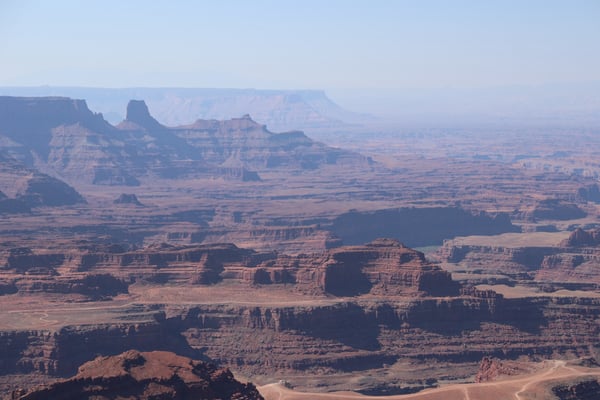 Vast desert landscape with layered red rock buttes and mesas extending toward the horizon, viewed from an elevated… — Dead Horse Point State Park, Moab, Arches & Canyonlands