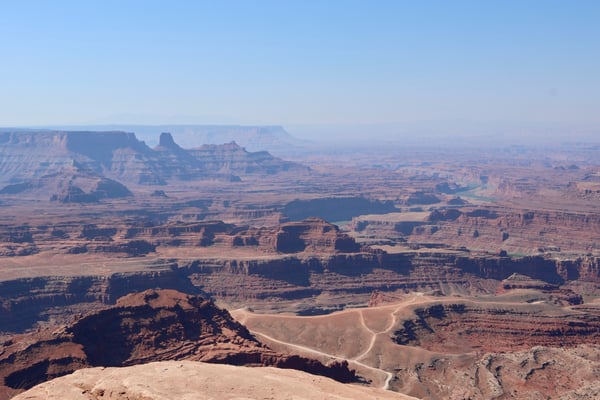 Aerial view of vast desert canyon landscape with layered red rock formations and winding road through Canyonlands… — Dead Horse Point State Park, Moab, Arches & Canyonlands