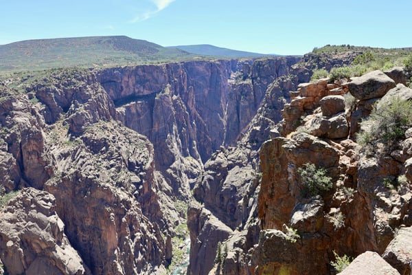 Deep narrow canyon with towering red rock walls viewed from Chasm View near Montrose, Colorado. — Black Canyon of the Gunnison