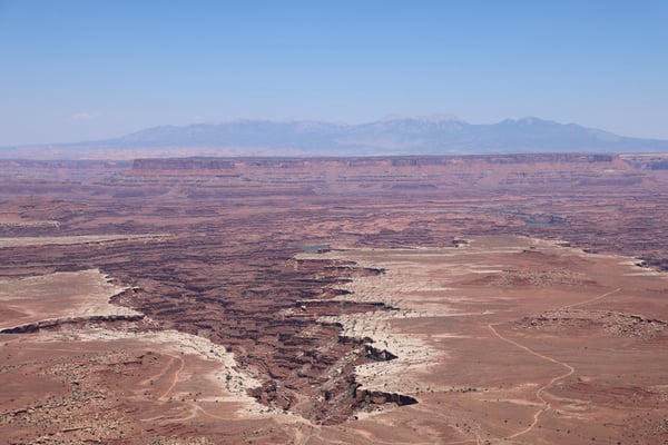 Vast desert landscape with layered canyonlands and distant mountains viewed from Buck Canyon Overlook near Moab, Utah. — Moab, Arches & Canyonlands