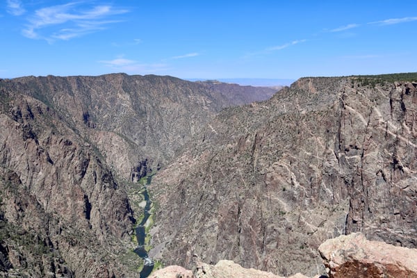 Deep canyon with a winding river visible far below, flanked by steep rocky cliffs and forested slopes at Dragon Point. — Dragon Point, Black Canyon of the Gunnison