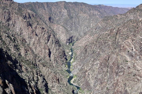 A dramatic canyon with steep rocky cliffs and a winding river visible far below, viewed from Dragon Point overlook. — Dragon Point, Black Canyon of the Gunnison