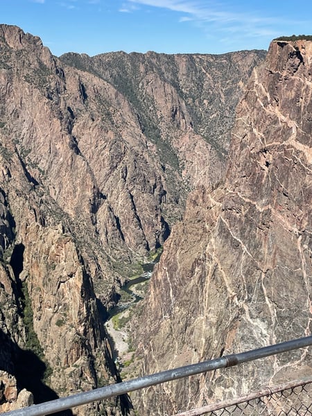Painted Wall View shows a deep canyon with steep rock walls and a river flowing through the base, viewed from a railed… — Painted Wall View, Black Canyon of the Gunnison