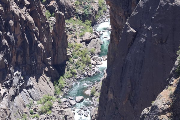 A turquoise river flows through a narrow rocky canyon at Chasm View, viewed from the canyon rim. — Chasm View, Black Canyon of the Gunnison