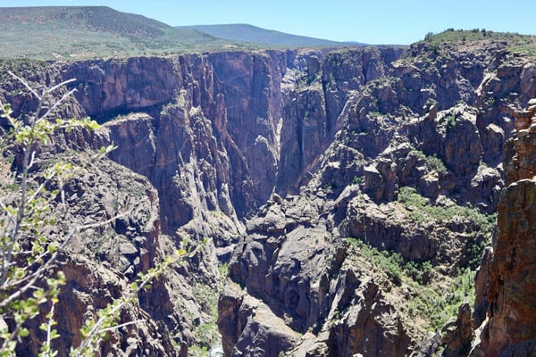 Dramatic deep canyon with towering columnar rock formations and sparse vegetation viewed from Chasm View overlook. — Chasm View, Black Canyon of the Gunnison