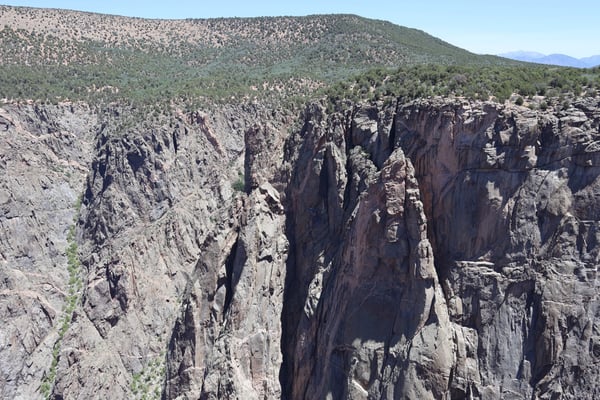 Tall columnar basalt cliffs with coniferous forest viewed from Chasm View overlook in Colorado. — Black Canyon of the Gunnison