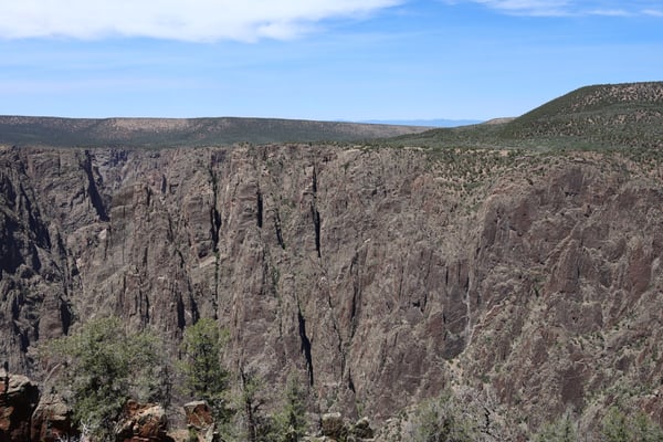 Dramatic columnar basalt cliffs with forested slopes viewed from Gunnison Point overlook in Colorado. — Gunnison Point, Black Canyon of the Gunnison