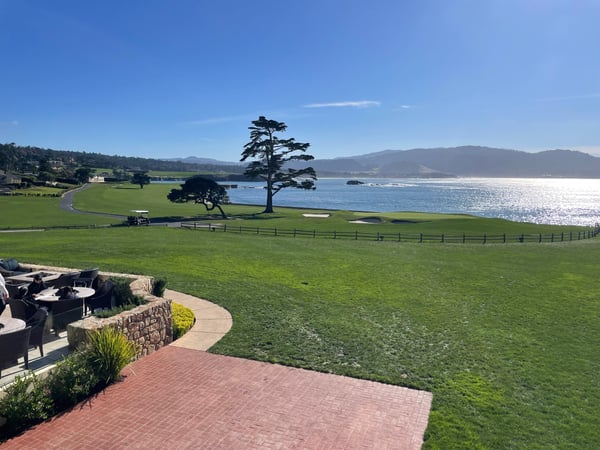 Manicured coastal golf course with cypress trees overlooking the Pacific Ocean, viewed from a terrace with fire pit. — Pebble Beach, Monterey & Carmel