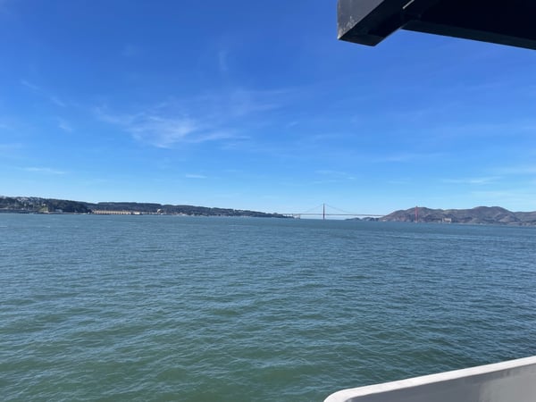 Golden Gate Bridge viewed from a ferry or boat in San Francisco Bay with Marin Headlands visible across the water.
