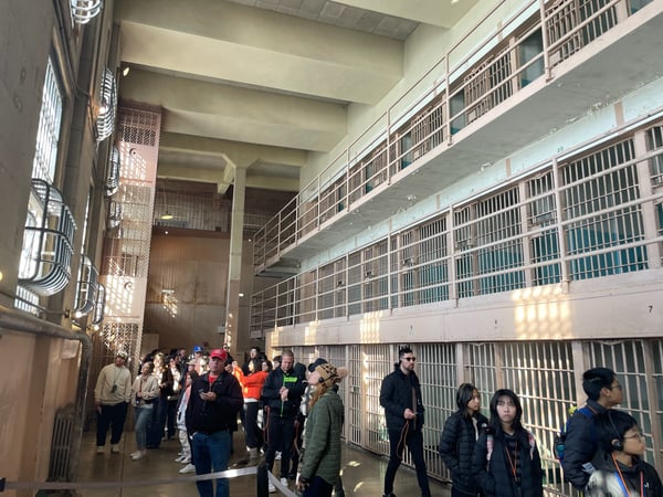 Tourists visit the multi-level cell block at Alcatraz Federal Penitentiary, with rows of barred cells visible across… — Alcatraz Island, San Francisco