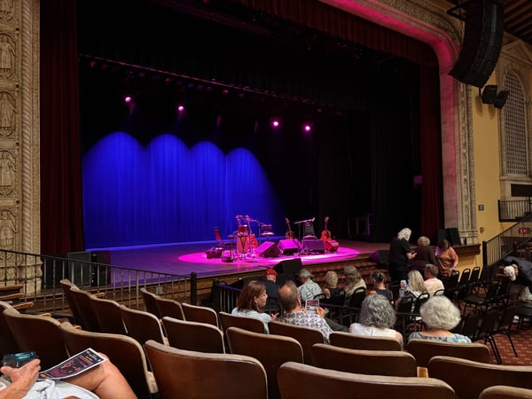 Live music performance on an ornate theater stage with blue curtains and pink stage lighting, viewed from the audience… — Philadelphia