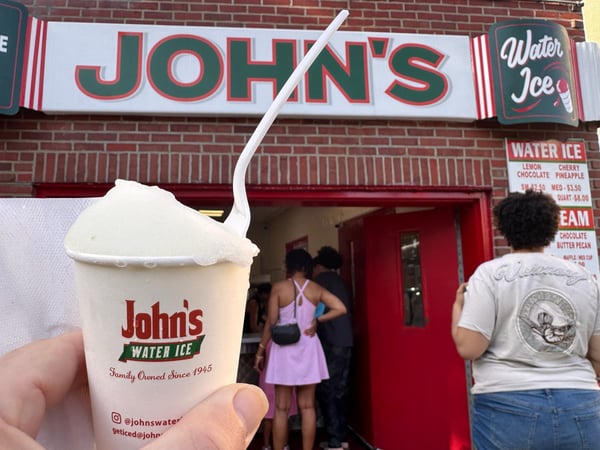 A hand holding a water ice cup from John's, a family-owned establishment since 1945, in front of the storefront in… — Center City, Philadelphia