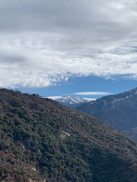 Forested mountain slopes with snow-capped peaks and a distant lake visible from a high elevation viewpoint in Sequoia… — Sequoia & Kings Canyon