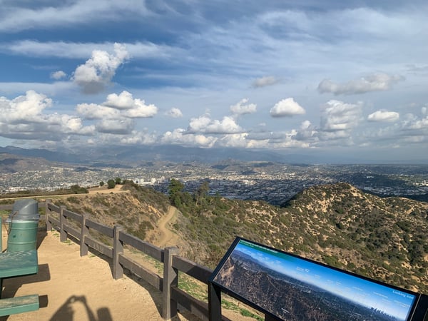Panoramic vista of Los Angeles basin and surrounding mountains from Griffith Park overlook with interpretive signage. — Griffith Park, Los Angeles