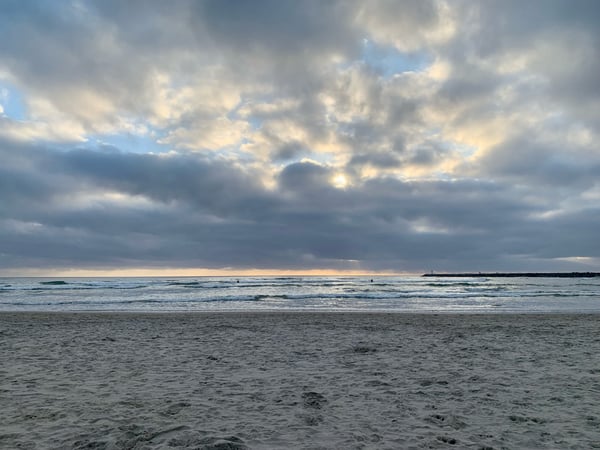 Sandy beach with gentle waves and dramatic cloudy sky at Point Loma, San Diego.