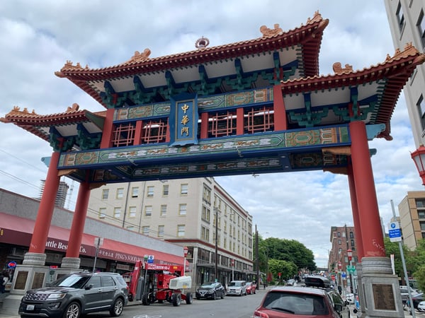 Ornate red and gold Chinese gate with traditional curved roofs in Seattle's Chinatown district, framing street-level…