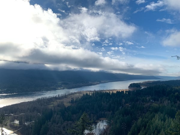 Lake surrounded by forested mountains and valleys viewed from an elevated overlook under partly cloudy skies. — Columbia River Gorge