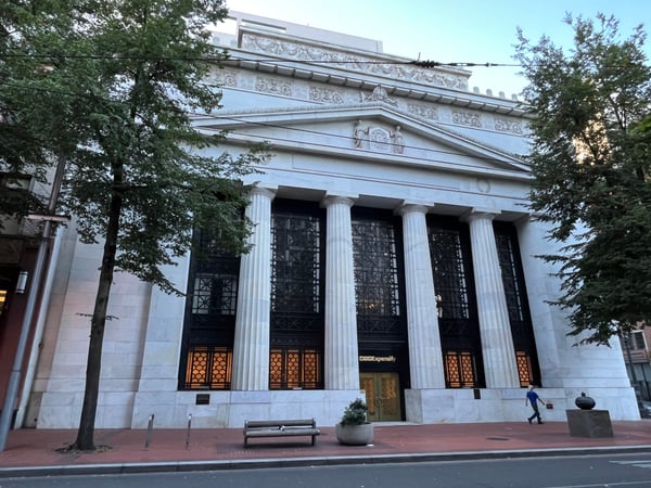 Neoclassical building with Corinthian columns and ornate pediment, viewed from street level with mature trees framing… — Downtown, Portland