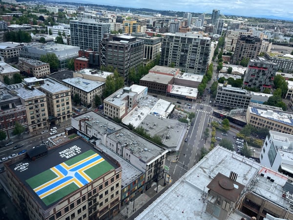 Aerial view of Portland downtown skyline with mixed-use buildings, streets, and a distinctive green and blue mural on a… — Downtown, Portland
