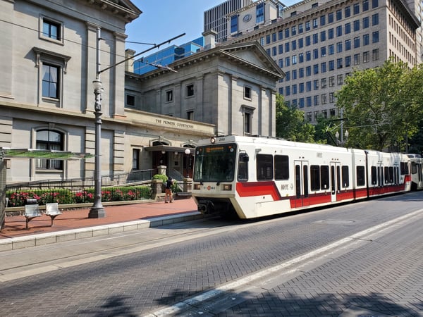 MAX light rail train passing The Pioneer Courthouse in downtown Portland, with historic and modern architecture framing… — Downtown, Portland