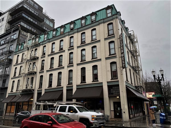 Historic brick building with green mansard roof and ground-floor storefronts on a wet street in downtown Portland… — Pearl District, Portland