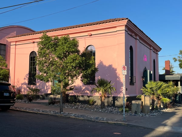 Coral-pink historic building with arched windows and desert landscaping in an urban neighborhood. — Portland
