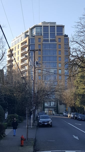Modern residential high-rise building with tan and glass facade viewed from street level in an urban neighborhood. — Goose Hollow, Portland