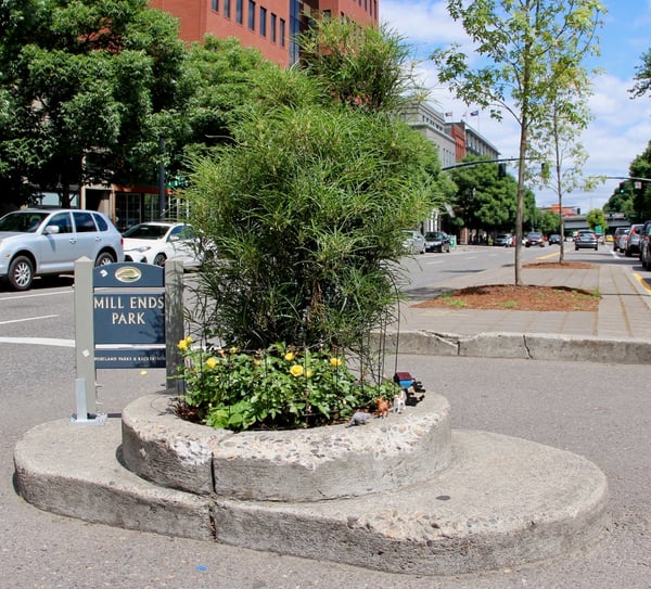 Mill Ends Park entrance with planted flowers and ornamental grasses in downtown Portland, viewed from street level. — Old Town, Portland