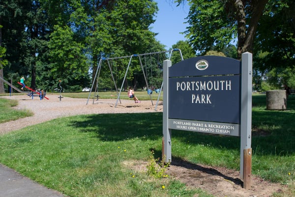 Portsmouth Park entrance sign with playground equipment and swings visible in Portland, Oregon.