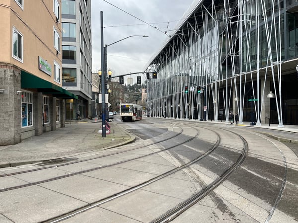 Modern urban streetscape with light rail tracks, contemporary architecture, and storefronts along a downtown transit… — Goose Hollow, Portland
