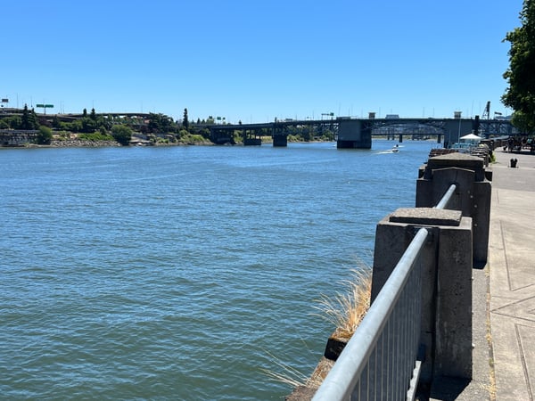 Willamette River viewed from a waterfront pier, with bridges and industrial structures spanning the water under clear… — Old Town, Portland