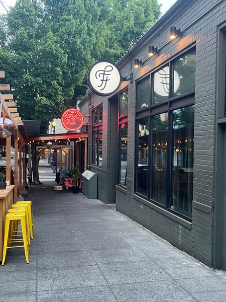 Modern restaurant storefront with neon signage and ivy-covered building in an urban alley at dusk. — Downtown, Portland