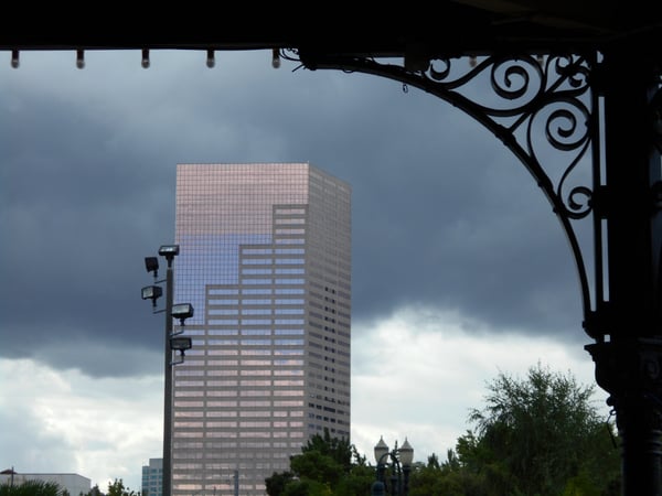 Modern high-rise office tower framed by ornate architectural detail, viewed from a covered structure in downtown… — Pearl District, Portland