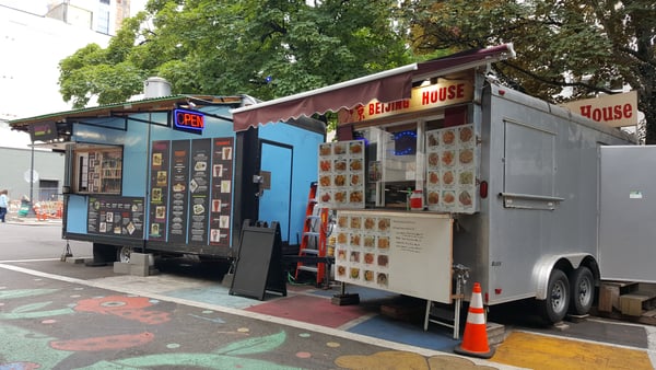 Food vendor trailers including Beijing House restaurant parked on a city street with colorful pavement art. — Downtown, Portland