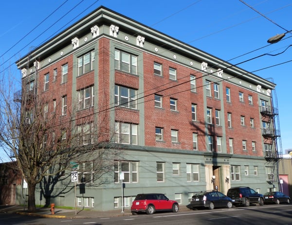 Early 20th-century brick apartment building with ornamental cornice and fire escapes, photographed from street level on… — Goose Hollow, Portland