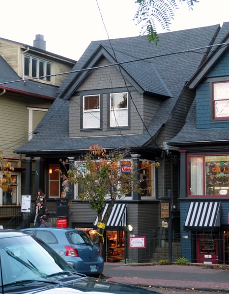 Street-level view of historic mixed-use buildings with retail storefronts and residential upper floors in autumn. — Northwest District, Portland